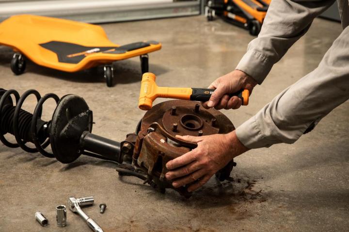 18 oz. Dead Blow Hammer being used by a person on a brake drum in a shop setting